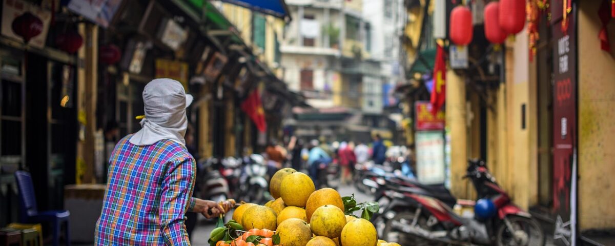 Person verkauft Obst auf belebter Straße in der Stadt.