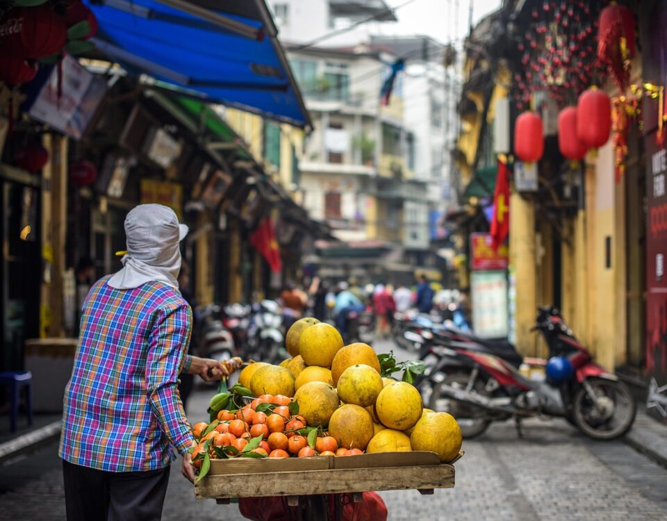 Person verkauft Obst auf belebter Straße in der Stadt.